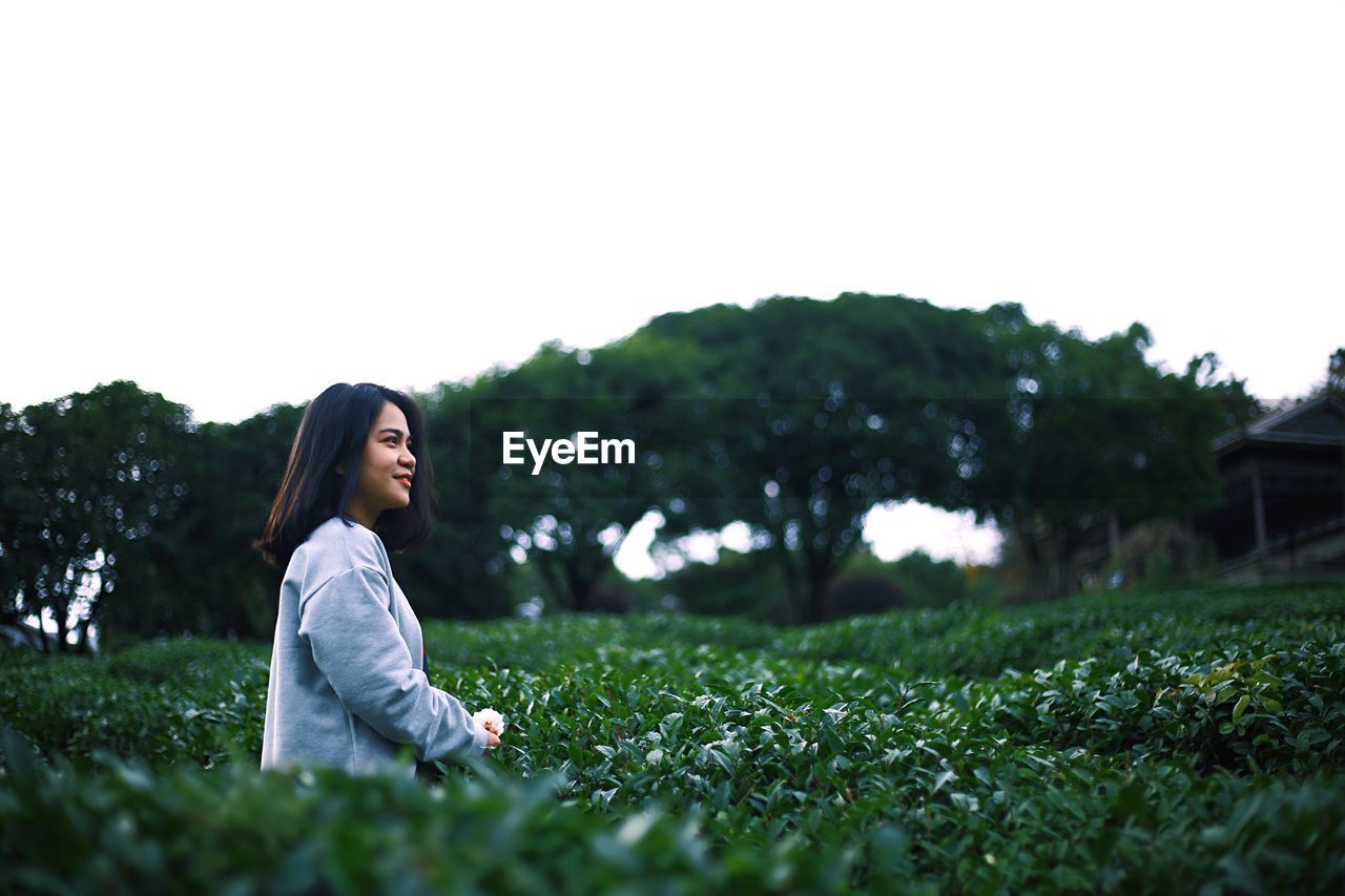 Woman smiling on field against clear sky