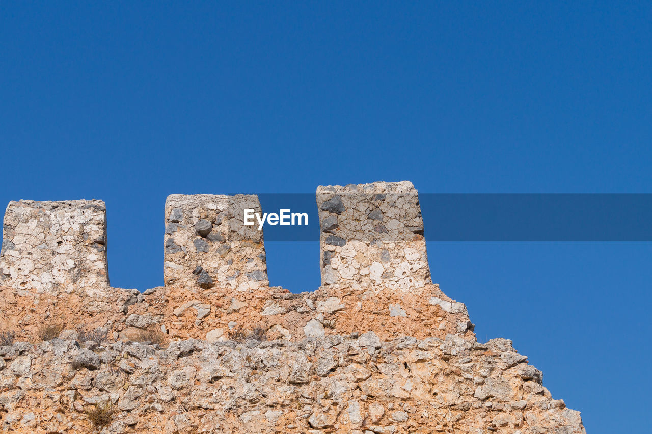 Low angle view of old ruins against clear blue sky on sunny day