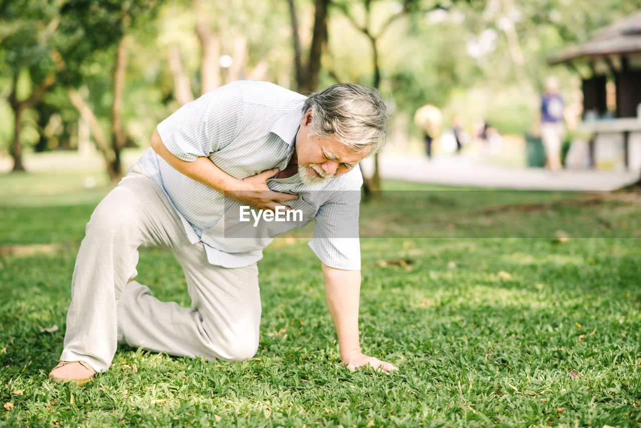 FULL LENGTH OF MAN CLIMBING ON GRASS AT PARK