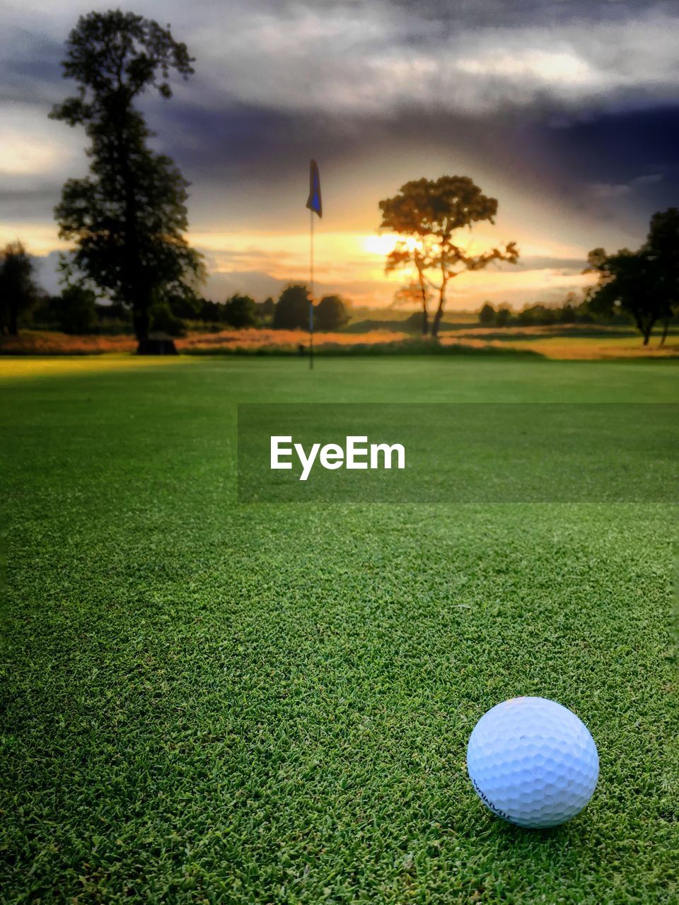 Golf ball on field against sky during sunset