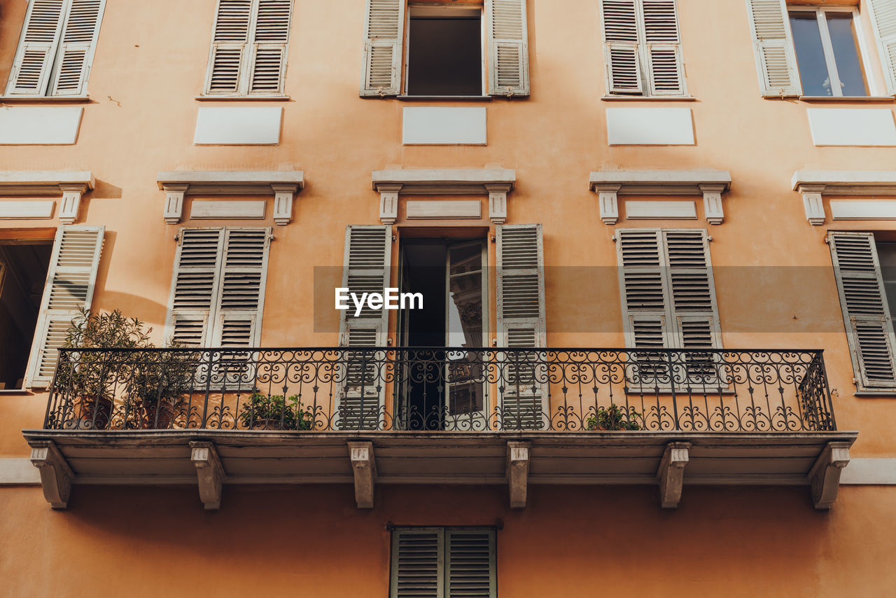 Low angle view of a traditional colourful apartment block building with a balcony in nice, france.