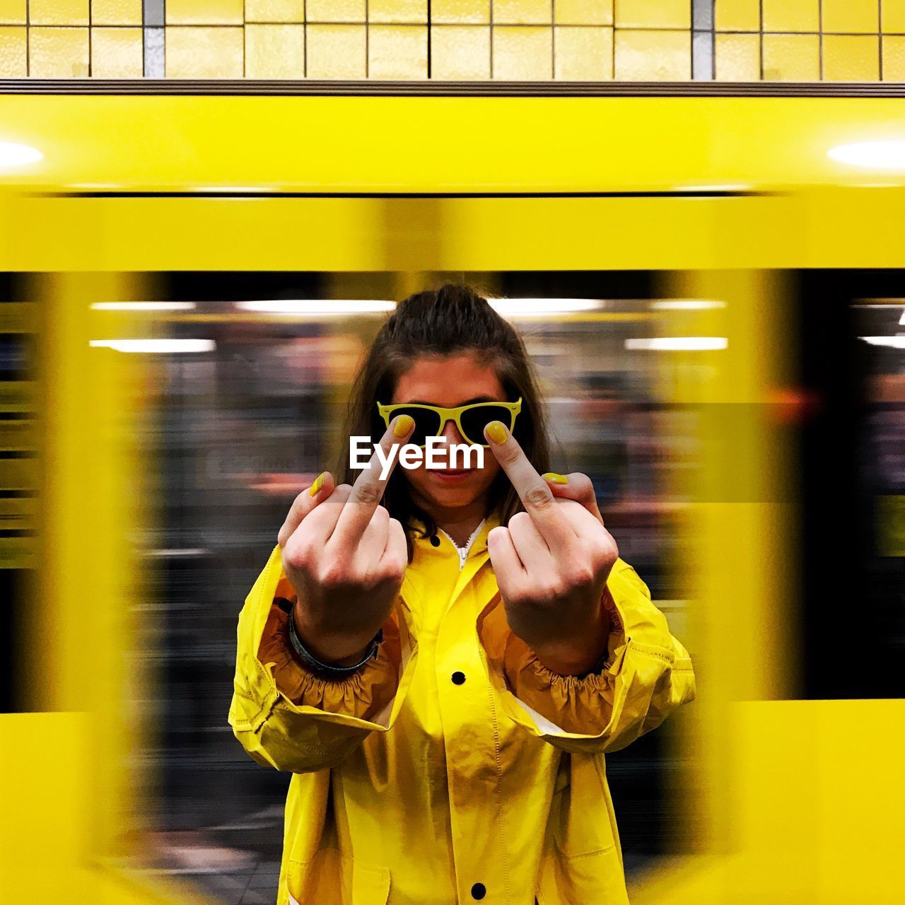 Woman showing middle finger against yellow light trail