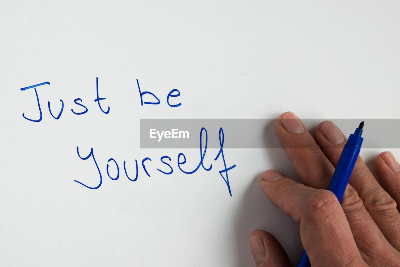 Close-up of hand holding felt tip pen by text on whiteboard