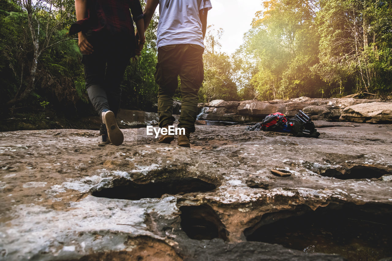 LOW SECTION OF MAN AND WOMAN STANDING ON ROCKS