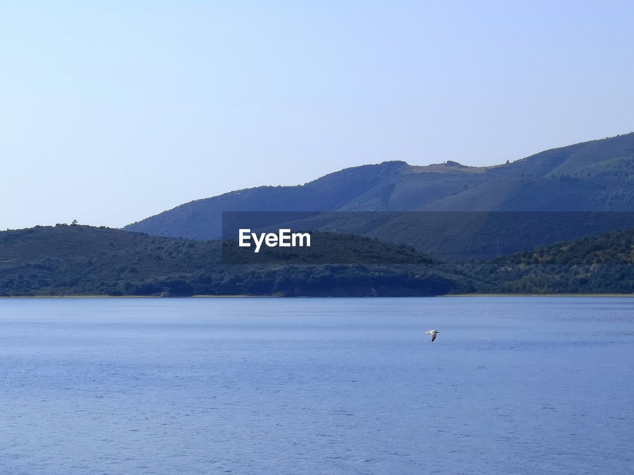 SCENIC VIEW OF SEA AND MOUNTAIN AGAINST CLEAR SKY