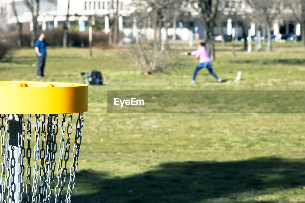 People playing flying disc golf sport game in the park or nature