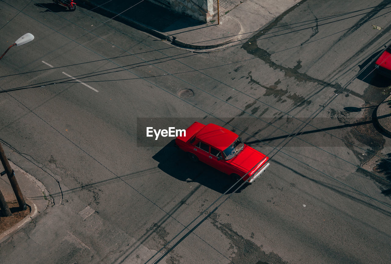 From above of asphalt road intersection with red vintage car among contemporary transports in middle in cuba