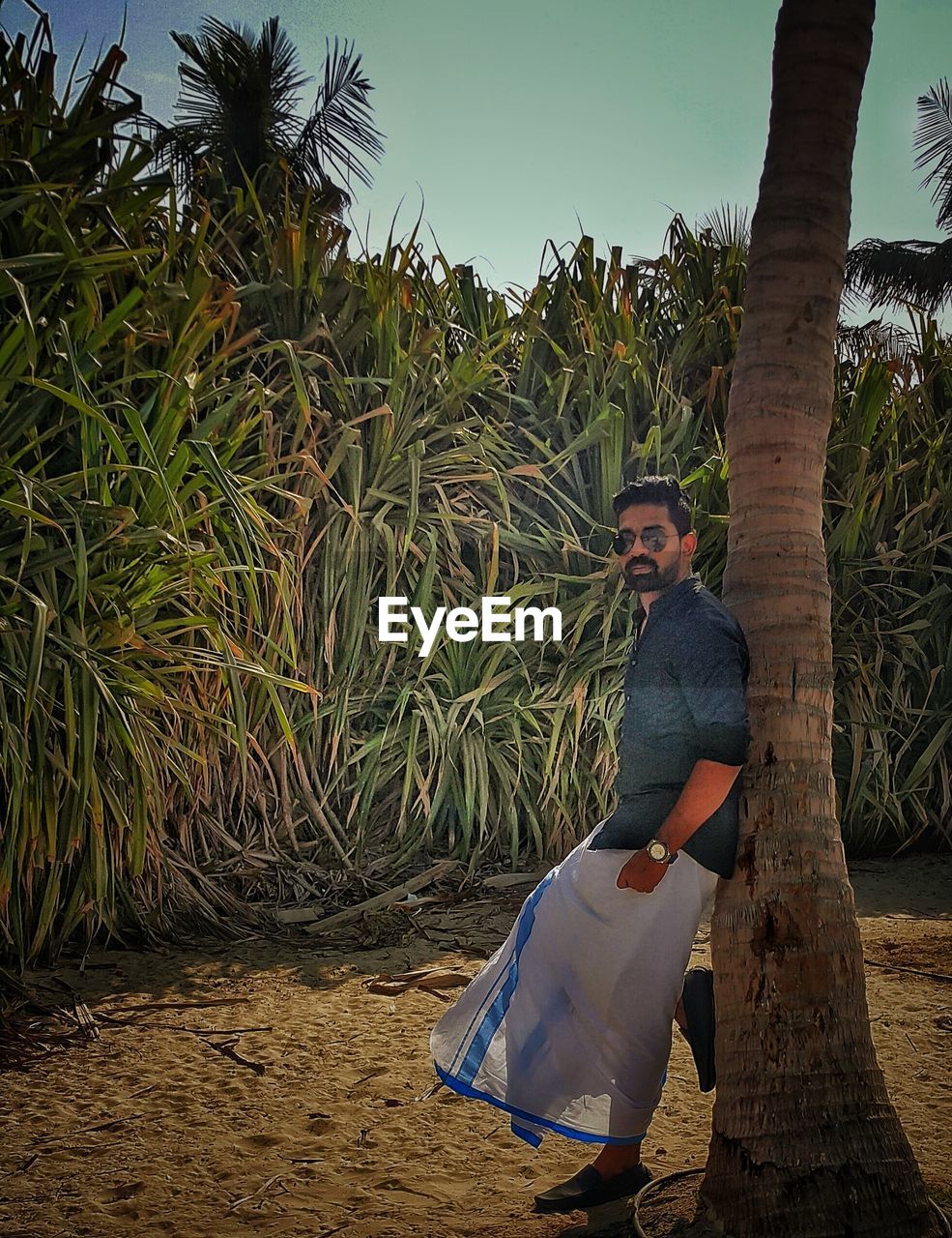 MAN STANDING ON FIELD AGAINST TREES