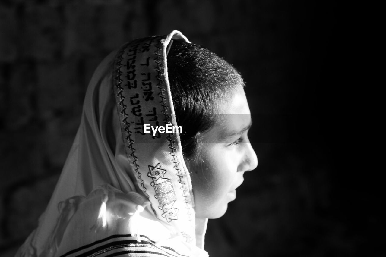 Side view of young man wearing headwear against wall