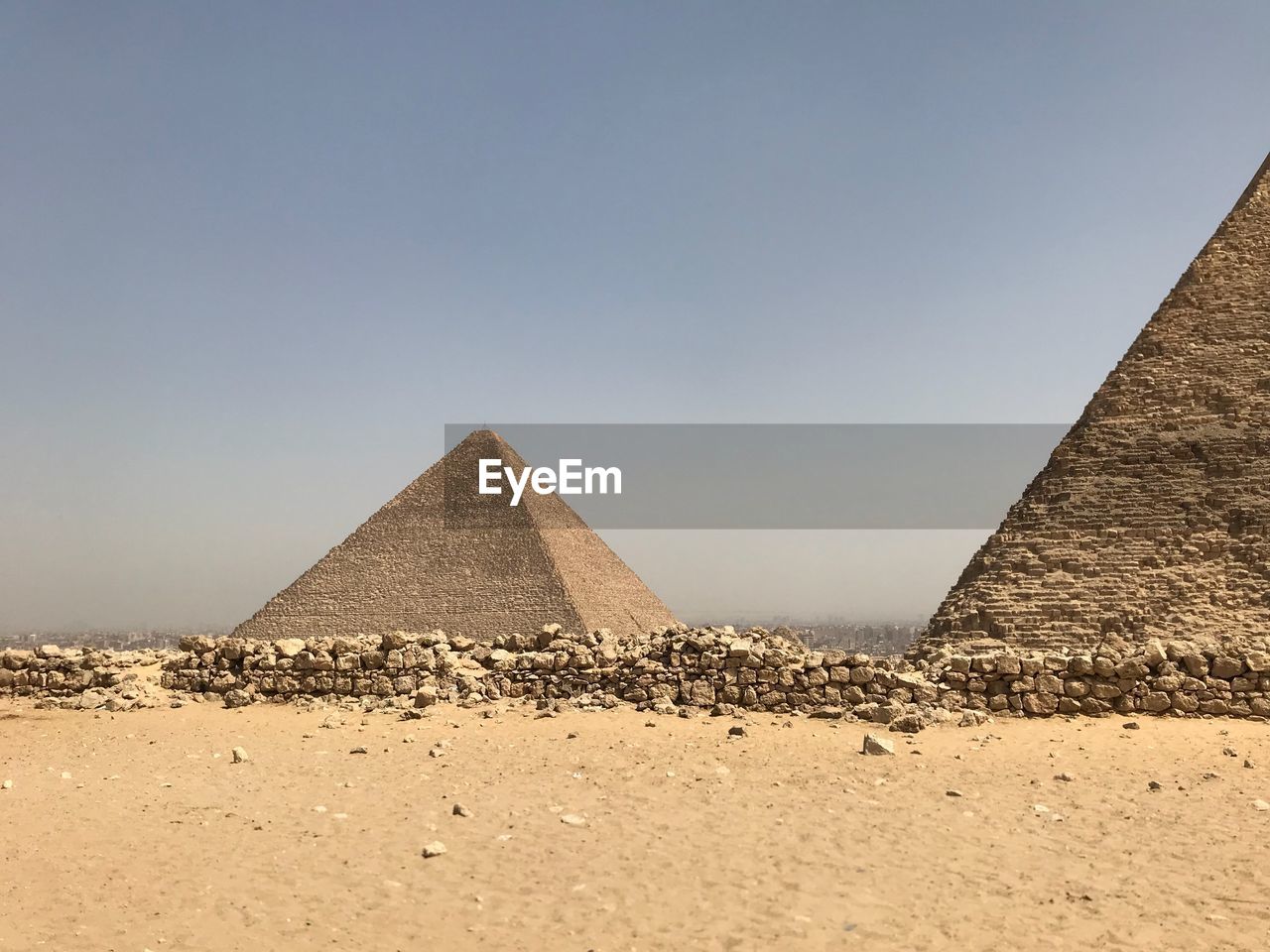 Pyramids on sand against clear sky