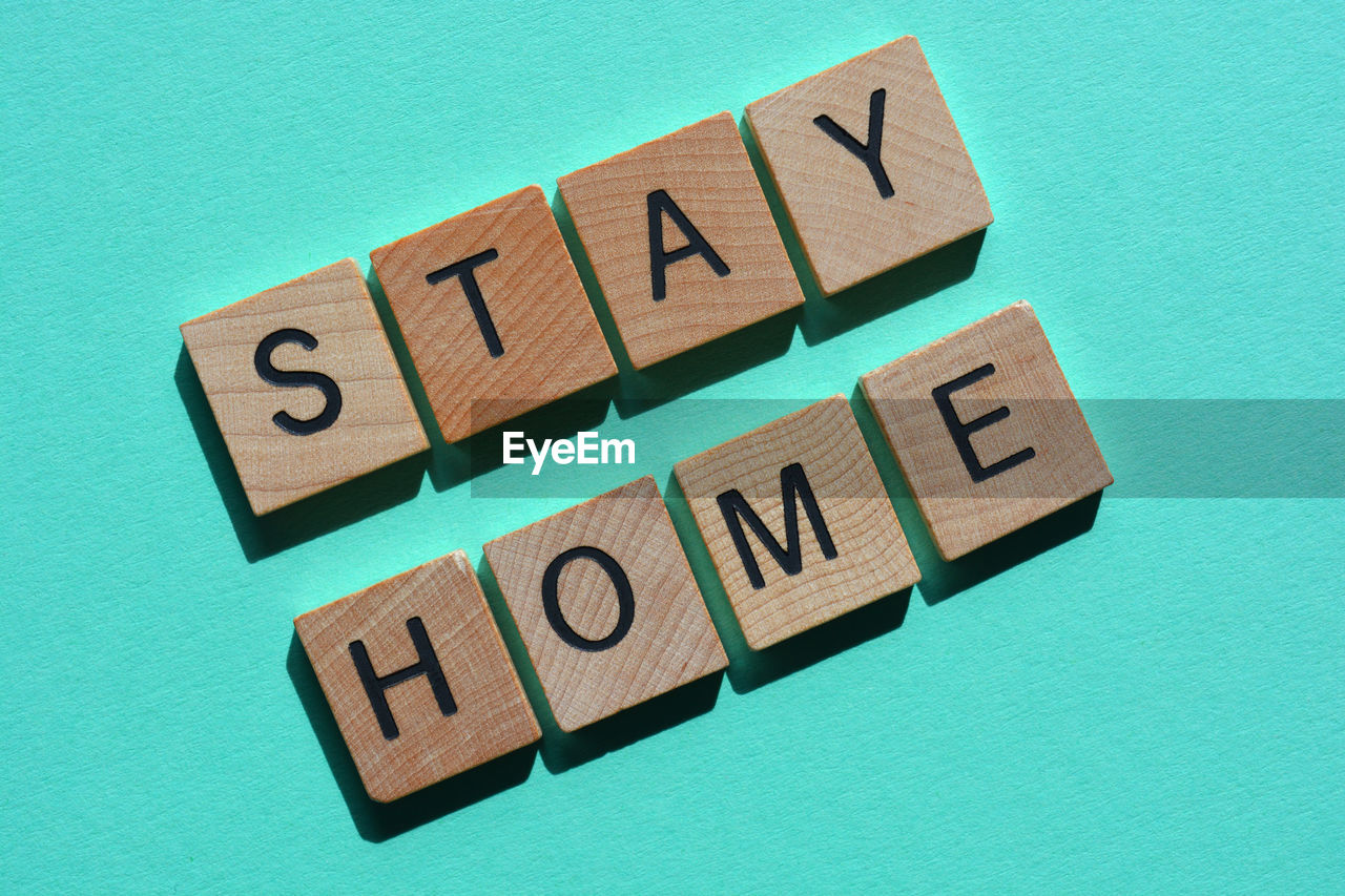 Stay home, words in wooden alphabet letters isolated on green