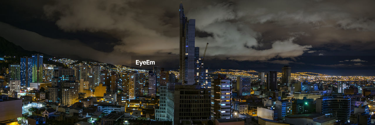 Aerial view of illuminated buildings against cloudy sky