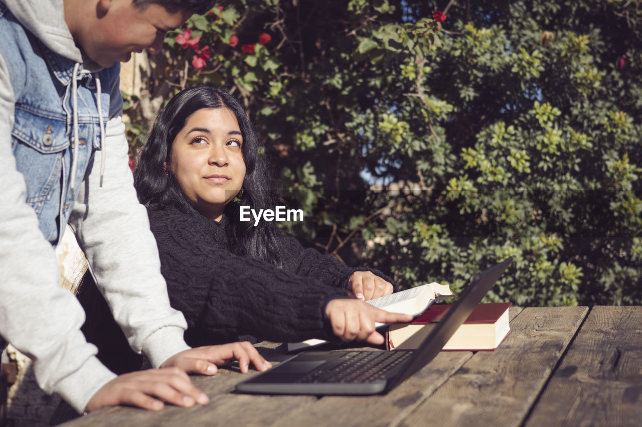 Two young men study outside school with laptops