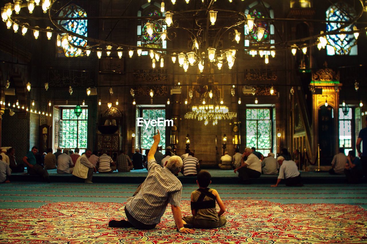 People sitting at illuminated blue mosque