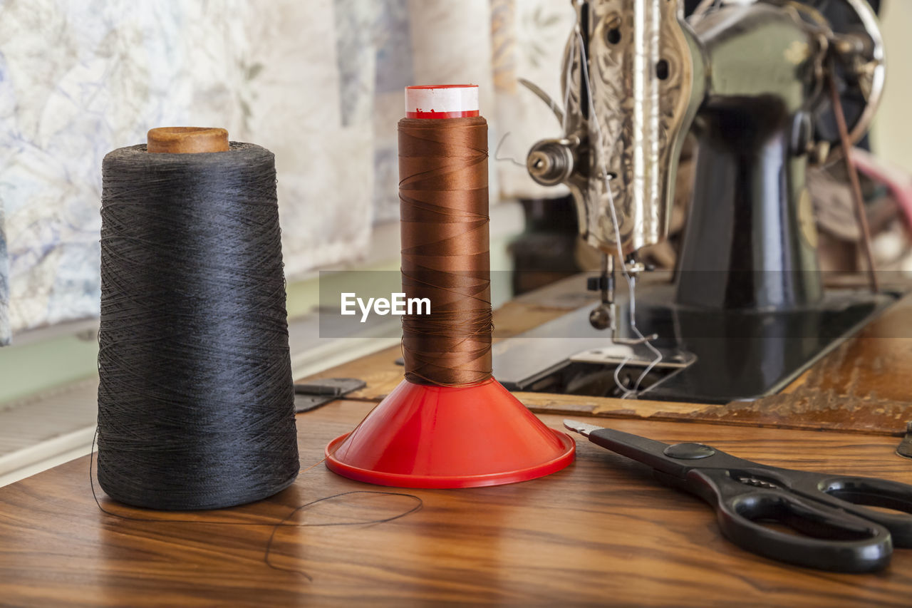 Close-up of thread spools by sewing machine