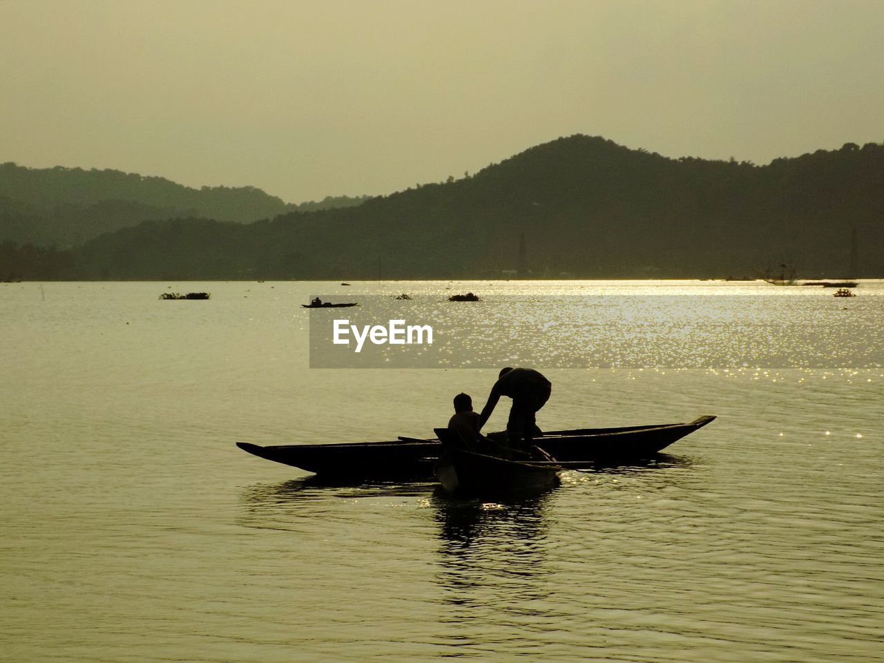 SILHOUETTE PEOPLE IN BOAT SAILING ON SEA AGAINST SKY