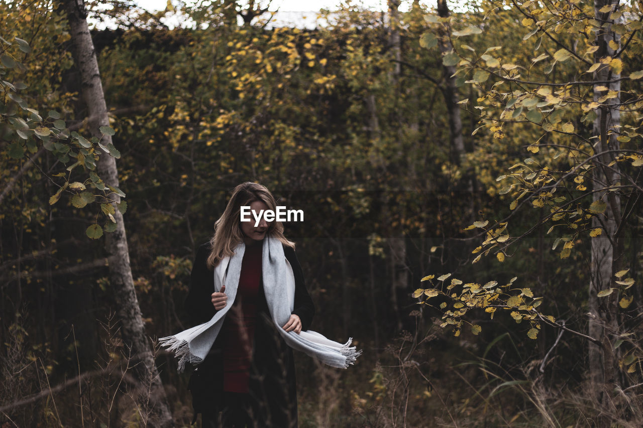 Mid adult woman with closed eyes standing against trees in forest