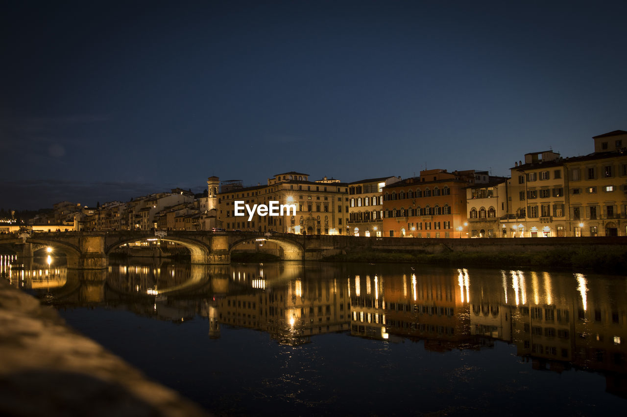 River by illuminated buildings against clear sky at night