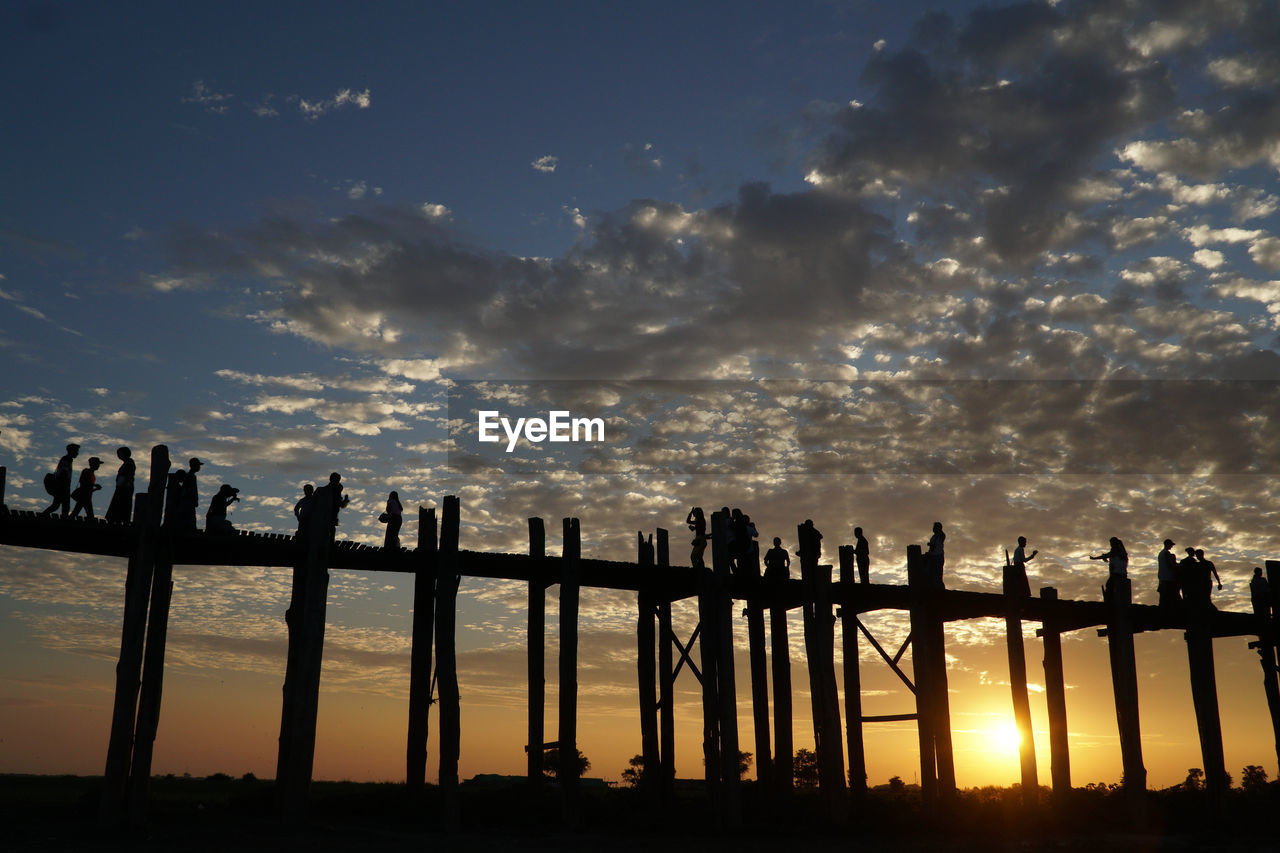 Silhouette of tourists walking enjoying u bein bridge in mandalay during sunset