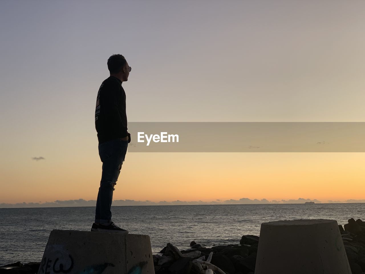 Man standing on beach against sky during sunset