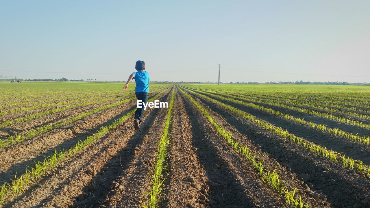 Side view of kid running in agricultural field