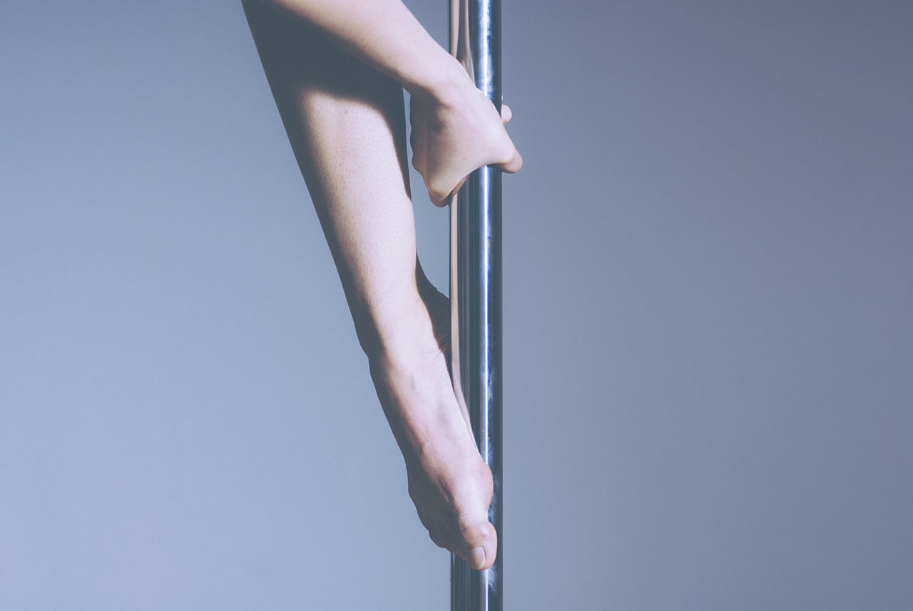 Midsection of pole dancer against gray background