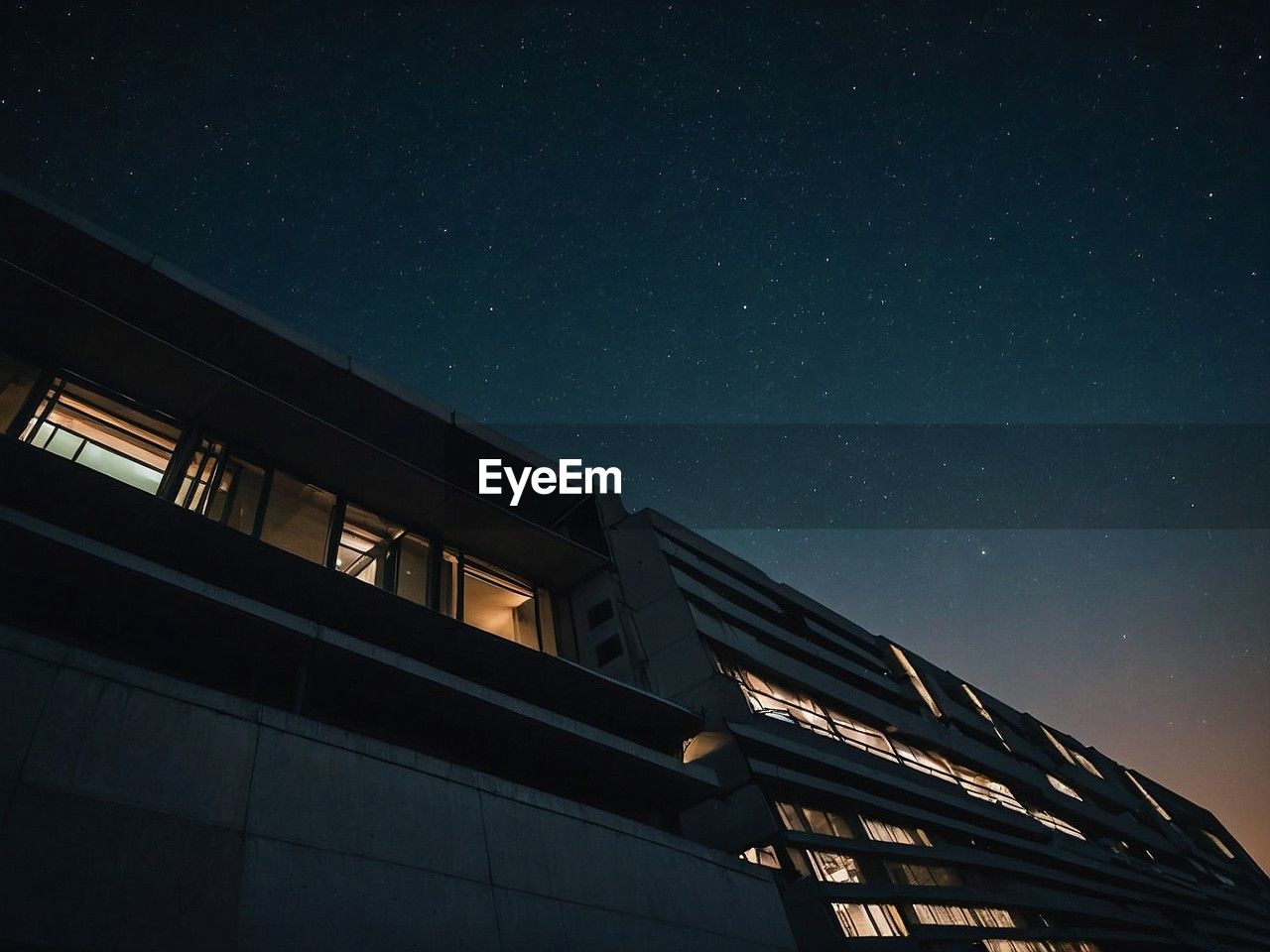 low angle view of modern building against sky at night