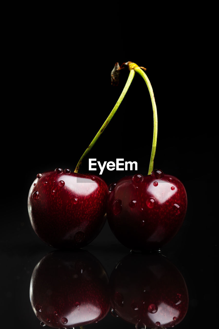 Close-up of wet cherries over black background