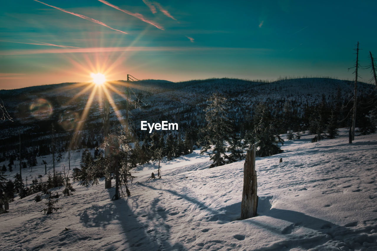 Scenic view of snow covered landscape against bright sun
