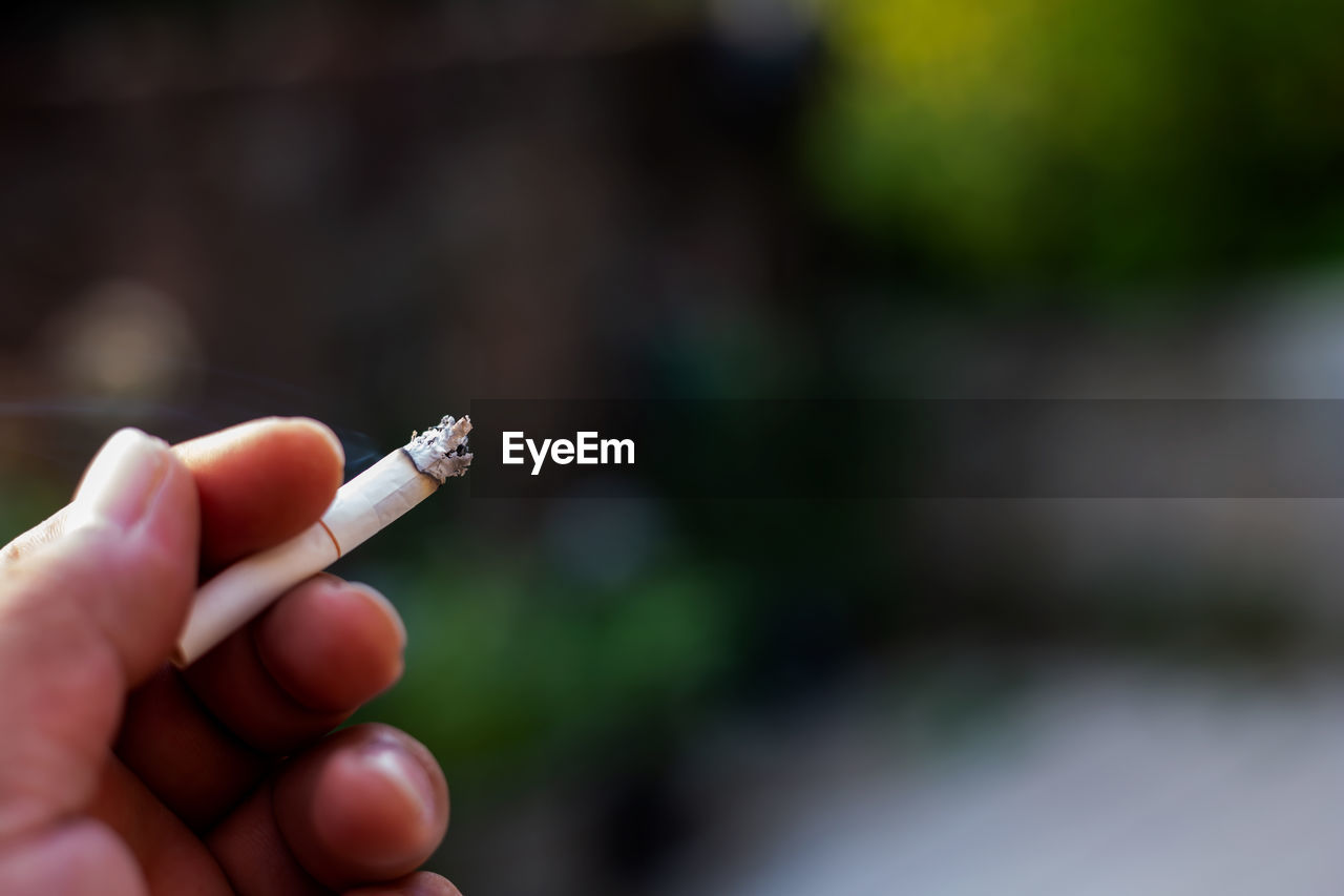 Close-up of hand holding cigarette