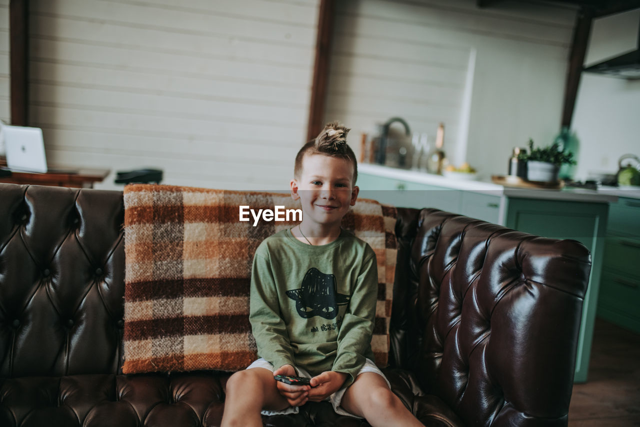 Portrait of smiling boy sitting on sofa