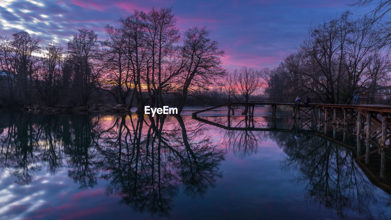 REFLECTION OF TREES IN LAKE AGAINST SKY