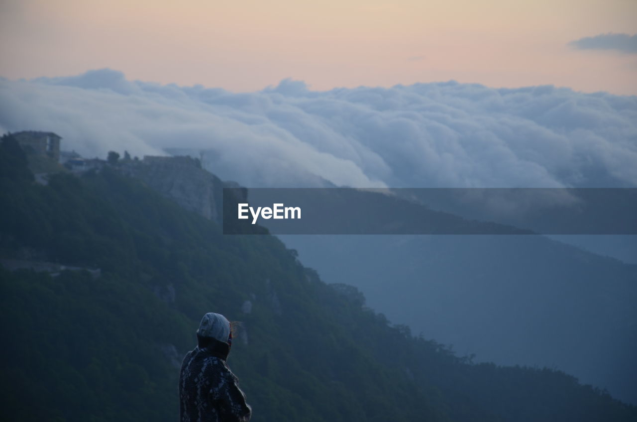 Rear view of man standing on mountain against sky