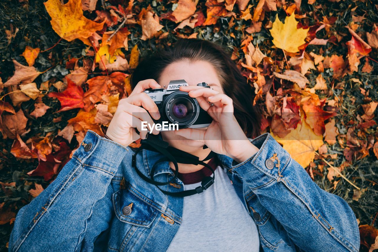 FULL LENGTH OF WOMAN PHOTOGRAPHING THROUGH AUTUMN LEAVES