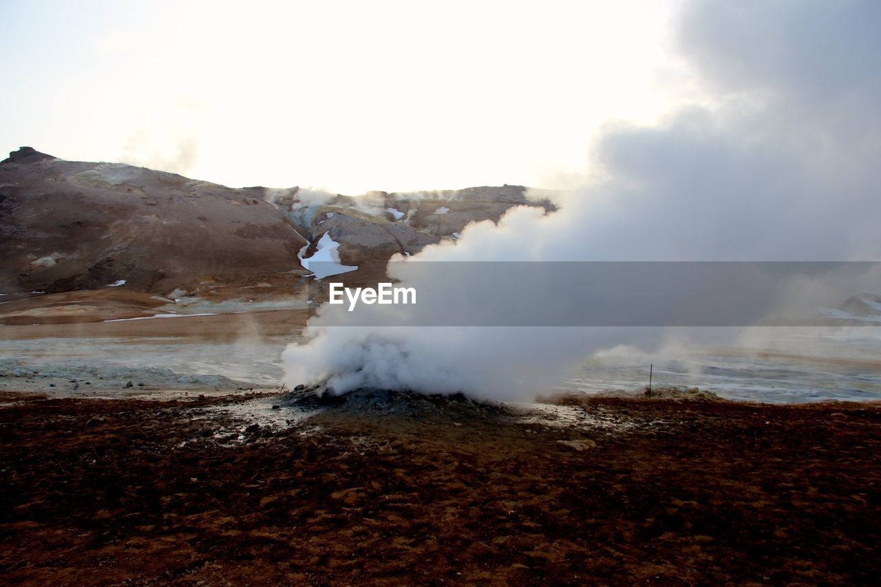 Steam emitting from geyser against sky