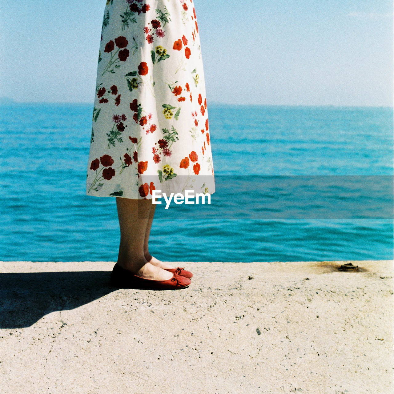 Low section of woman standing at beach