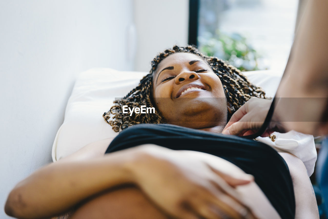 Cropped hand of doctor examining pregnant woman lying on bed in hospital