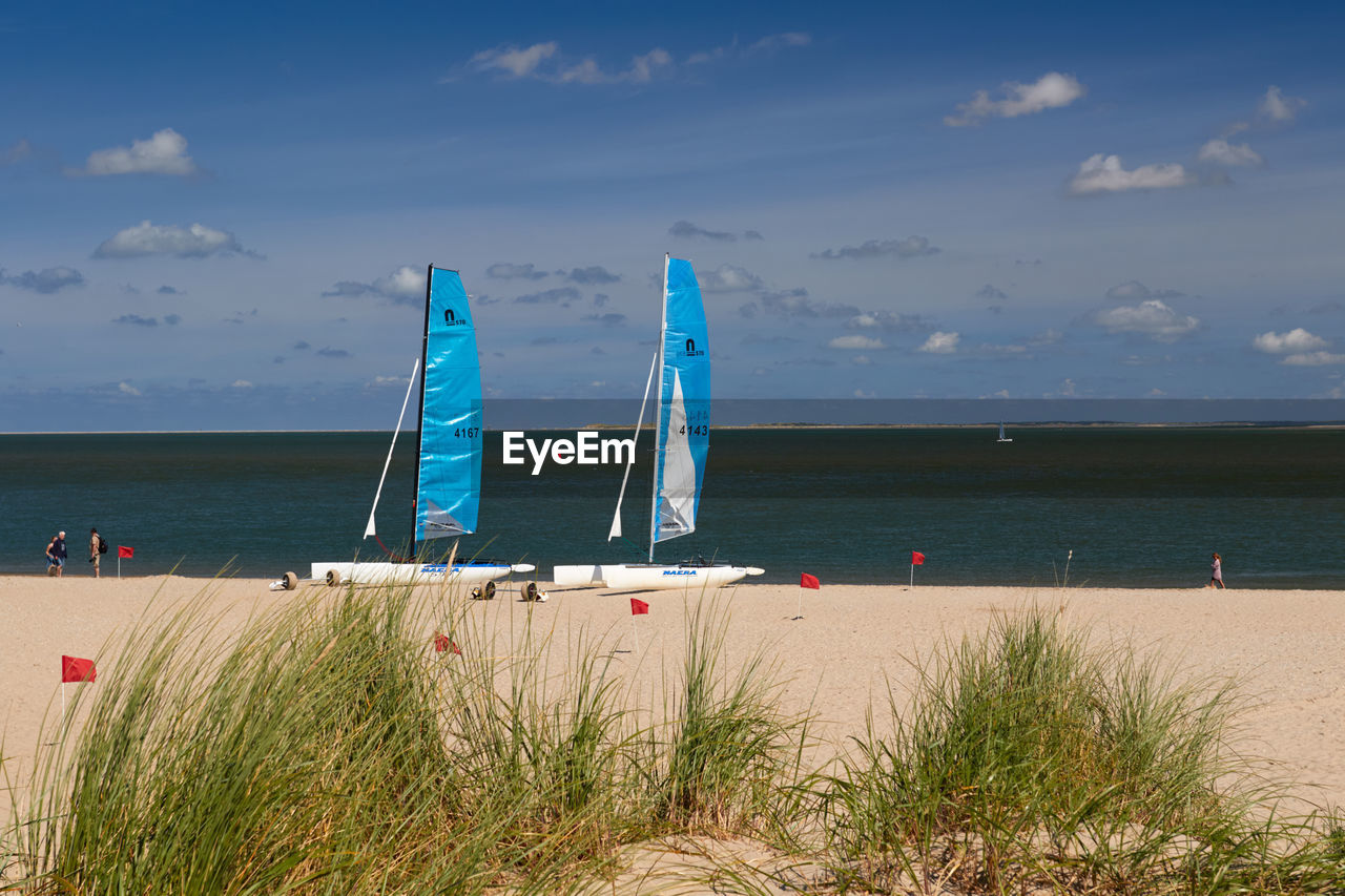 SAILBOATS ON BEACH AGAINST SKY