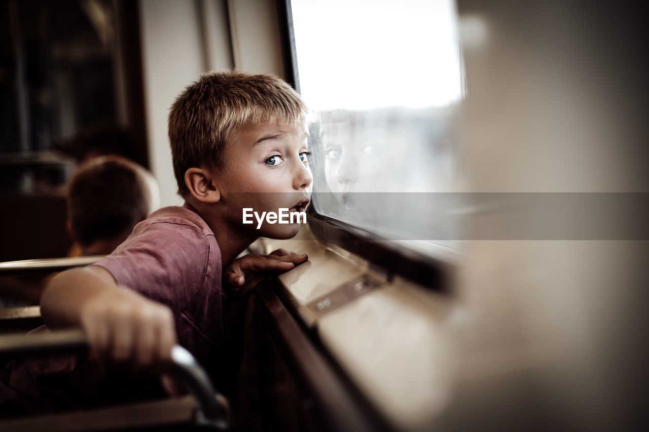 Boy looking through window in train