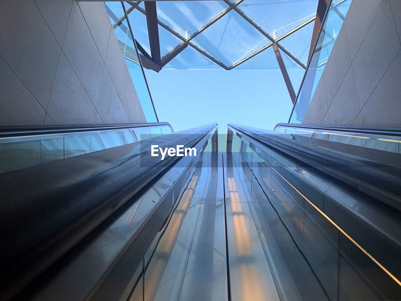 Low angle view of escalator railings against sky in city