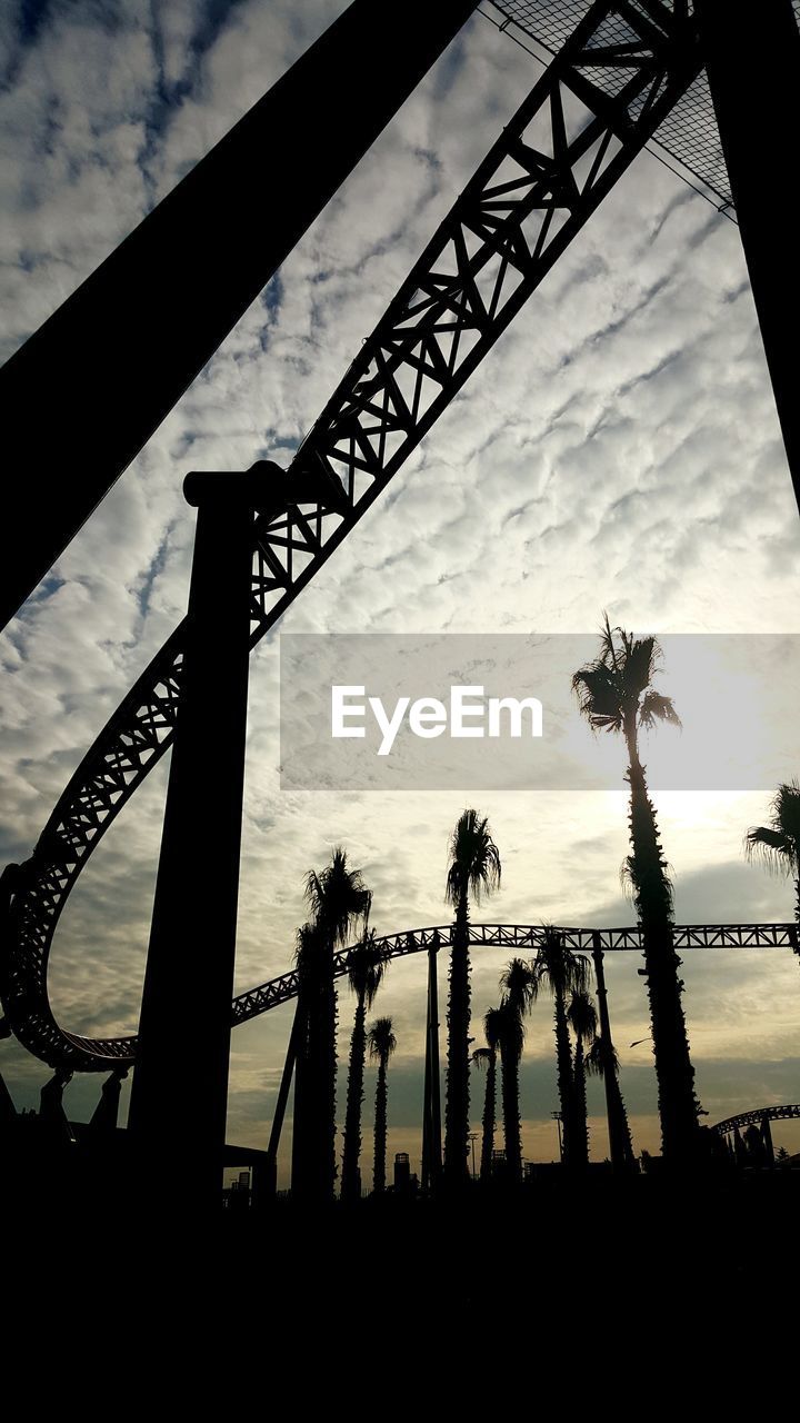 Low angle view of silhouette rollercoaster against cloudy sky during sunset