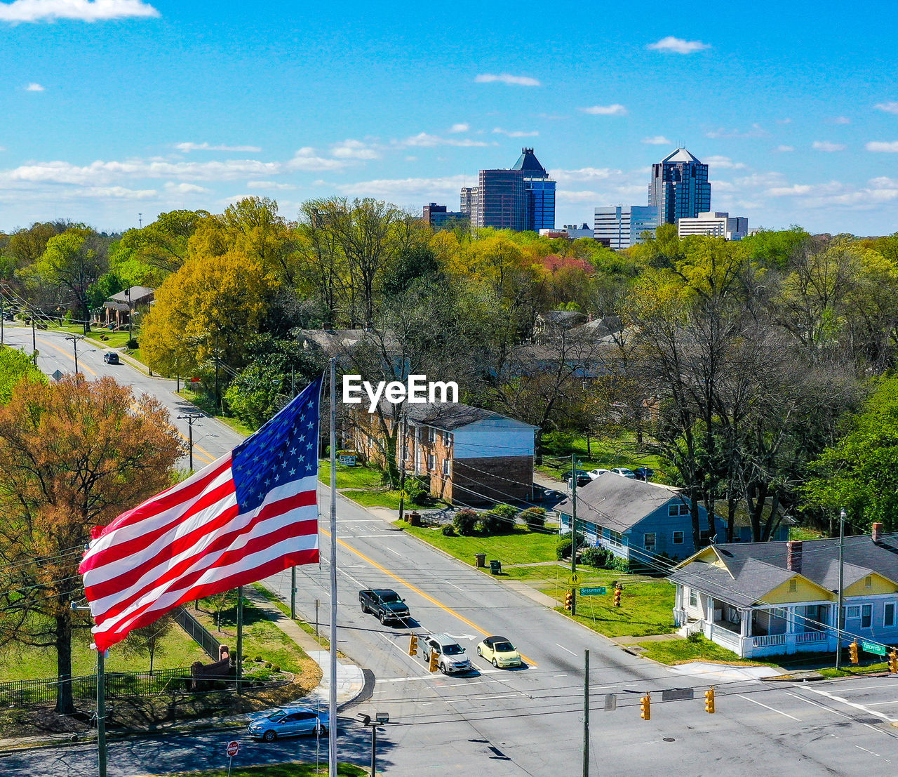 architecture, flag, building exterior, built structure, patriotism, city, sky, tree, building, nature, plant, landmark, striped, park, blue, no people, travel destinations, cityscape, landscape, outdoors, street, transportation, day, residential area, town, cloud, urban area, symbol, office building exterior, travel, road, residential district, vacation, skyline, environment, downtown, skyscraper, pole