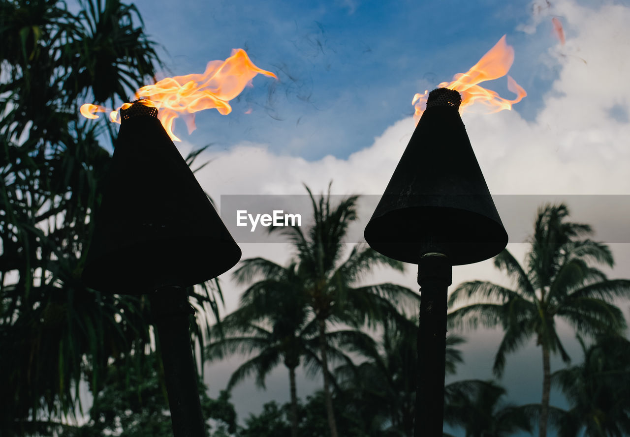 Low angle view of hawaiian tiki lanterns hanging against sky during sunset 