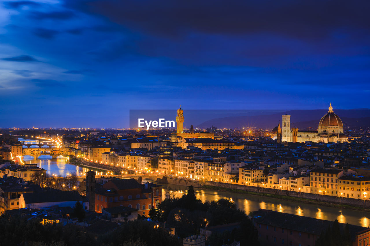Aerial view of illuminated cityscape against blue sky at dusk