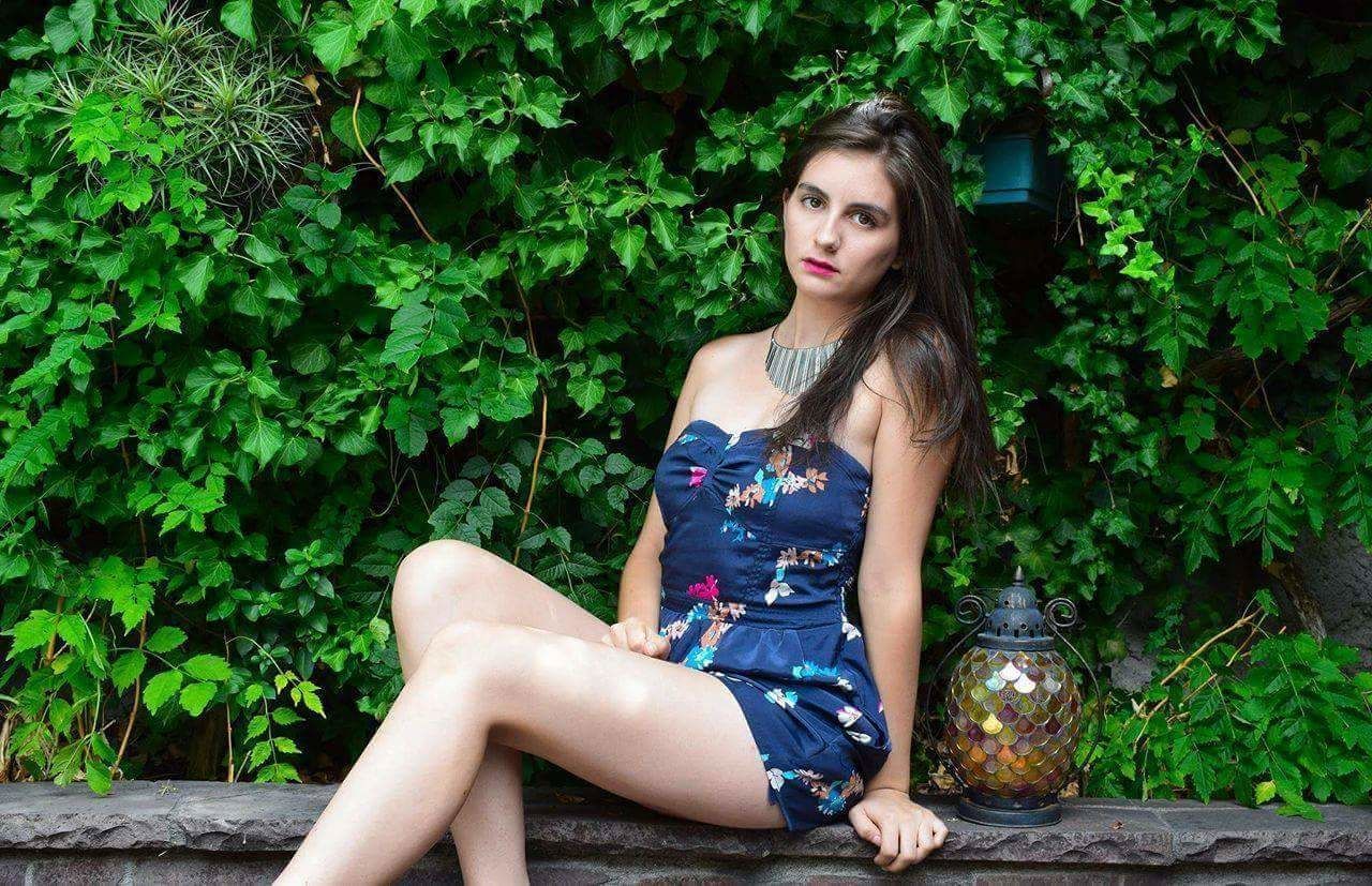 Portrait of beautiful woman sitting by lantern against plants