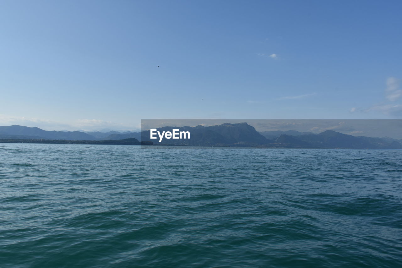 SCENIC VIEW OF SEA AND MOUNTAINS AGAINST CLEAR SKY