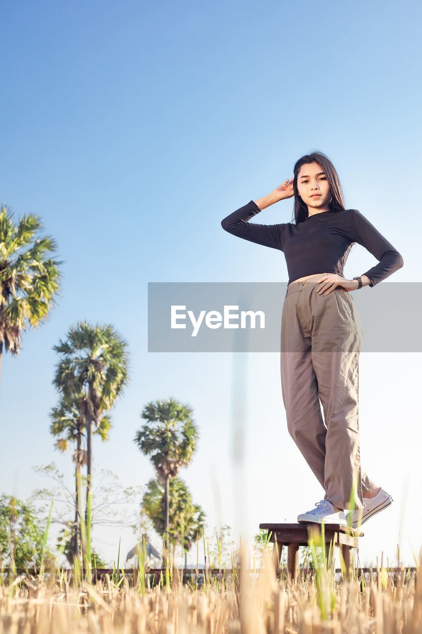 Low angle view of woman standing against clear sky