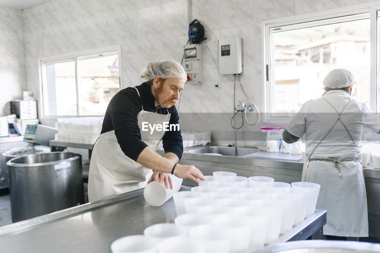 Mature chef couple working in dairy factory