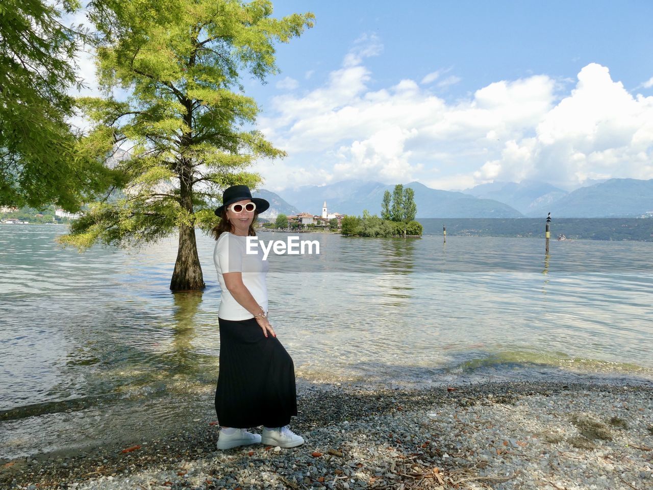 Woman standing by tree against sky