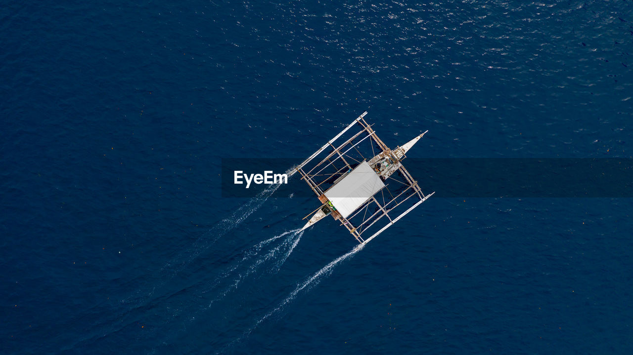 HIGH ANGLE VIEW OF SAILBOAT SAILING IN SEA AGAINST STAR FIELD